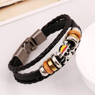 Bracelet multi-rangs en cuir noir avec breloques métalliques et anneaux marron et or pour homme.