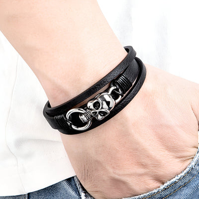 Bracelet multi-rangs en cuir noir avec tête de mort argentée et anneau métallique élégant.