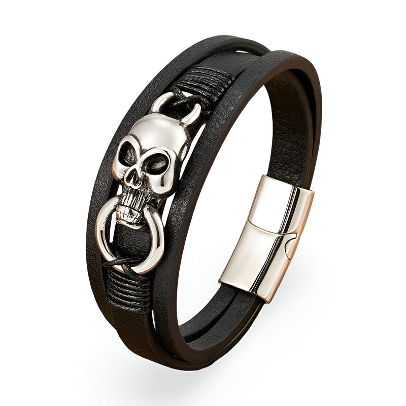 Bracelet multi-rangs en cuir noir avec tête de mort argentée et anneau, fermoir métallique brillant.