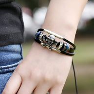 Bracelet multi-rangs en cuir noir avec tête de mort pirate argentée et barrette métallique fine.