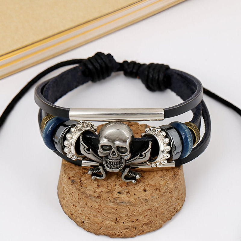 Bracelet multi-rangs en cuir noir avec tête de mort pirate argentée et perles bleues et argentées.