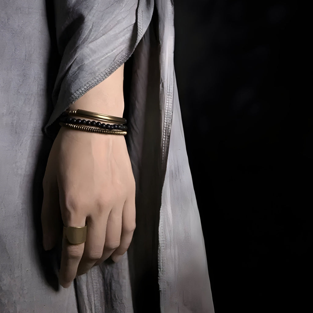 Bracelet multi-rangs en cuivre et pierres volcaniques marron et noir autour du poignet avec bague cuivrée assortie.