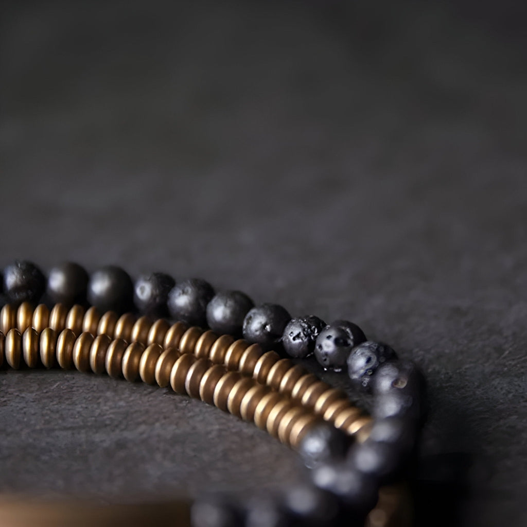 Bracelet multi-rangs en cuivre doré et pierres volcaniques noires, design élégant et texturé.