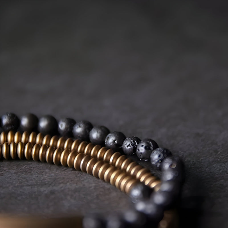 Bracelet multi-rangs en cuivre doré et pierres volcaniques noires, design élégant et texturé.