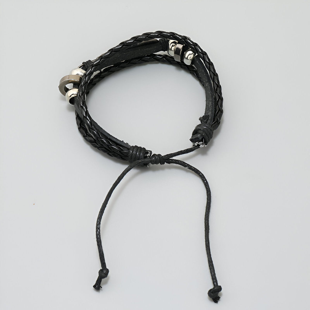 Bracelet multi-rangs noir en microfibre tressée avec plume métallique et fermoir coulissant.