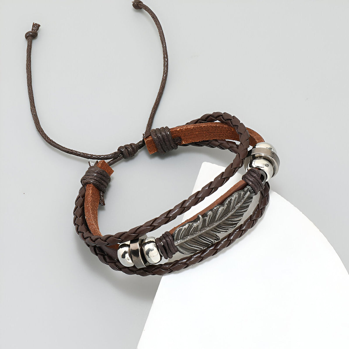 Bracelet multi-rangs en microfibre marron avec grande plume métal argenté et perles décoratives.