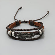 Bracelet multi-rangs marron en microfibre avec grande plume métallique gravée et cordons ajustables.