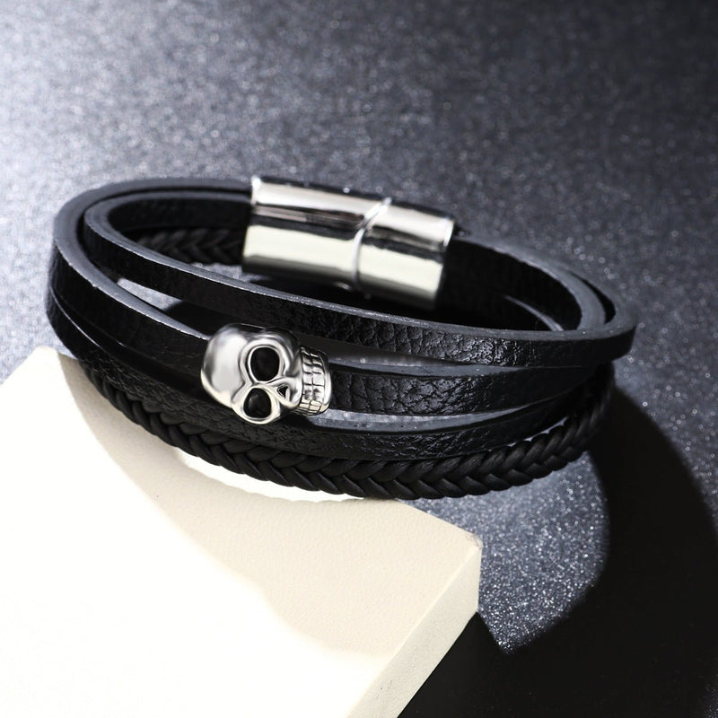 Bracelet multi-rangs noir en microfibre avec tête de mort argentée et fermoir magnétique.