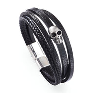 Bracelet multi-rangs noir en microfibre avec tête de mort argentée et fermeture aimantée.