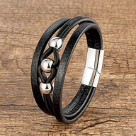 Bracelet multi-rangs en microfibre noire avec breloques métalliques argentées et fermoir magnétique.
