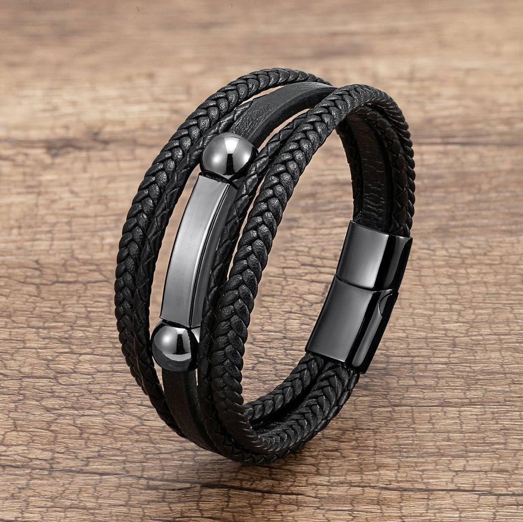 Bracelet homme multi-rangs noir en microfibre avec détails métalliques brillants et fermoir magnétique.