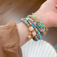 Bracelet multi-rangs pour femme avec perles élastiques bleu, blanc, rose et or, style bohème chic.