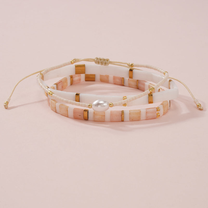 Bracelet multi-rangs perles japonaises crème et rose avec perle coquillage centrale et détails dorés, fermoir ajustable.