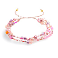 Bracelet multi-rangs en perles heishi rose, violet et transparent avec cordon réglable rose pâle.