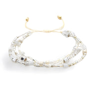 Bracelet multi-rangs en perles heishi blanches et argentées avec ajustement coulissant doré.