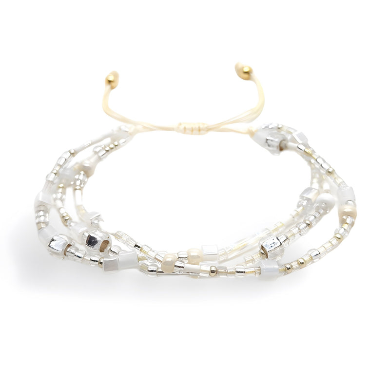 Bracelet multi-rangs en perles heishi blanches et argentées avec ajustement coulissant doré.