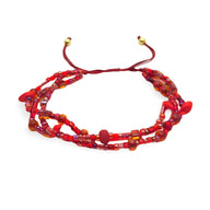 Bracelet multi-rangs en perles heishi rouges avec cordon ajustable et petites boules dorées aux extrémités.