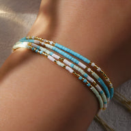 Bracelet multi-rangs en perles heishi bleu, blanc, rose et doré, style délicat pour femme.