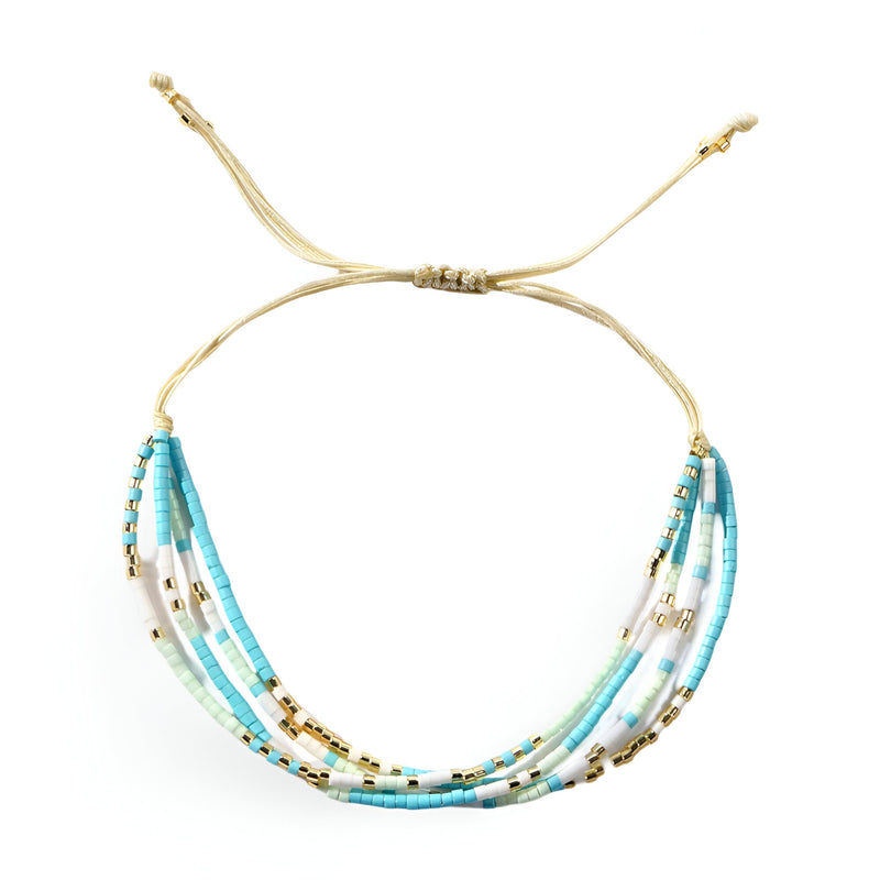 Bracelet multi-rangs en perles heishi bleu clair et turquoise avec perles dorées et cordon beige ajustable.