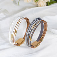 Bracelet multi-rangs blanc, marron et gris avec fermoir magnétique doré et détails métalliques bohémiens.