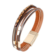 Bracelet multi-rangs en cuir marron avec détails métalliques dorés et fermoir magnétique carré.
