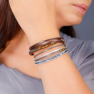 Bracelet multi-rangs en cuir marron et beige avec détails métalliques dorés et argentés style bohème.