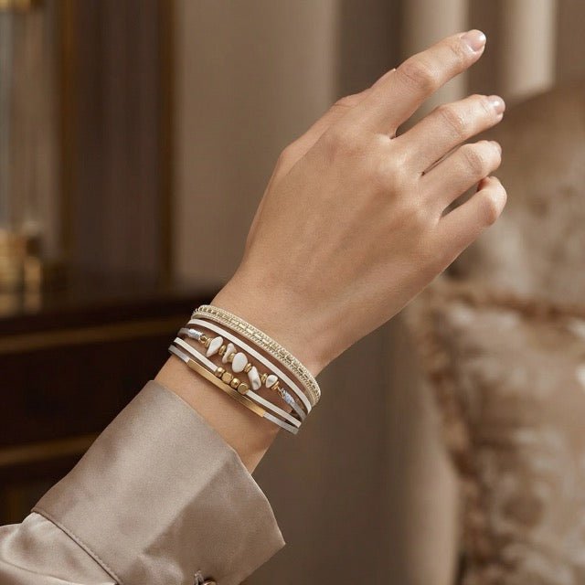 Bracelet multi-rangs beige avec perles dorées et pierres naturelles, style bohème élégant.