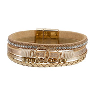 Bracelet multi-rangs beige simili cuir avec strass, anneaux dorés décoratifs et fermoir magnétique.