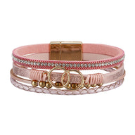 Bracelet multi-rangs rose en simili cuir vegan avec strass brillants, anneaux dorés décoratifs et fermoir magnétique doré.