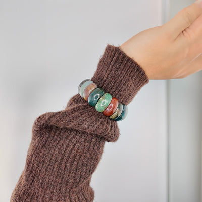 Bracelet élastique en pierres d'agate colorées rondes, nuances de vert, orange et marron, style naturel et estival.