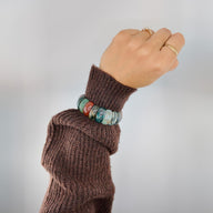 Bracelet en pierres d'agate multicolores avec tons bleus, verts, rouges et ocres, sur poignet féminin, style naturel et.