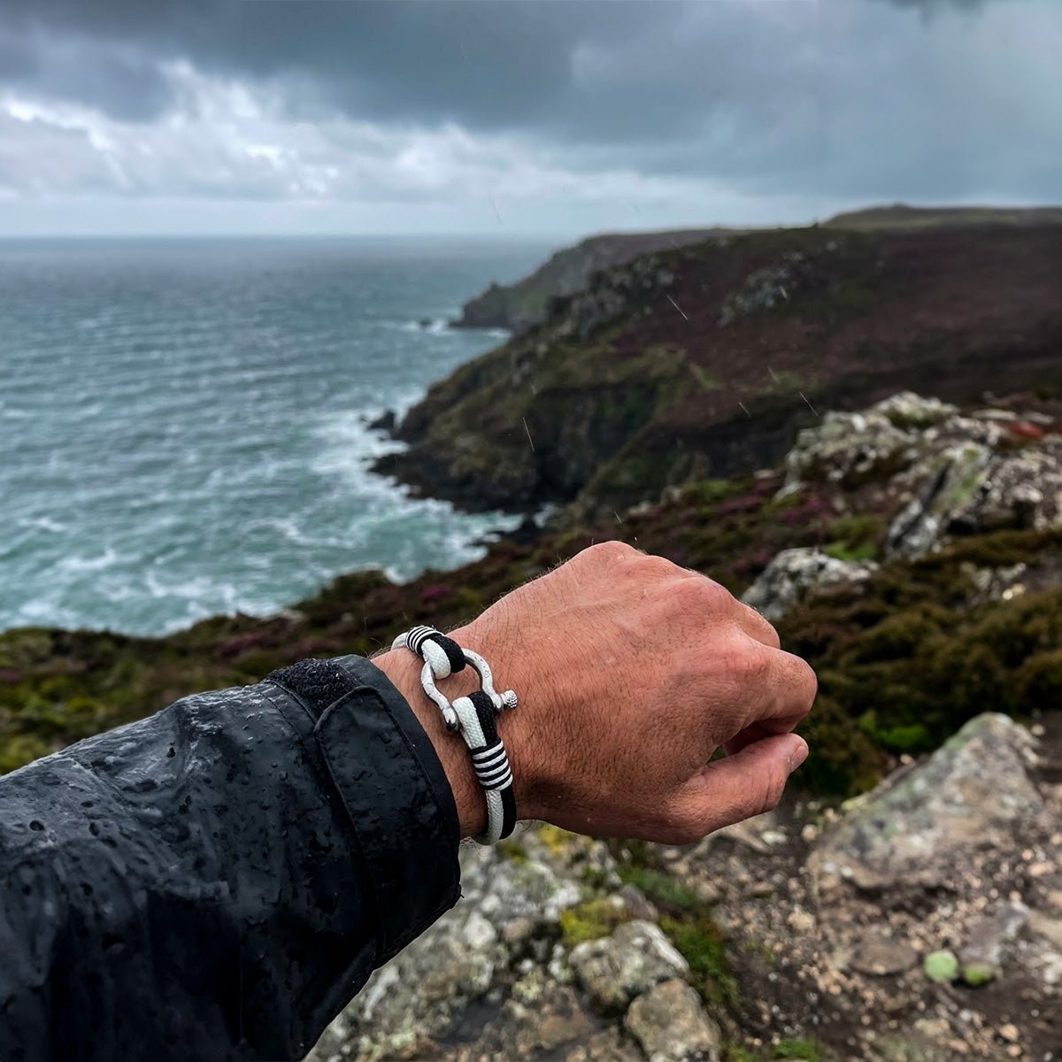 Bracelet nautique en nylon tressé noir et blanc avec fermoir manille en acier inoxydable, style marin élégant.