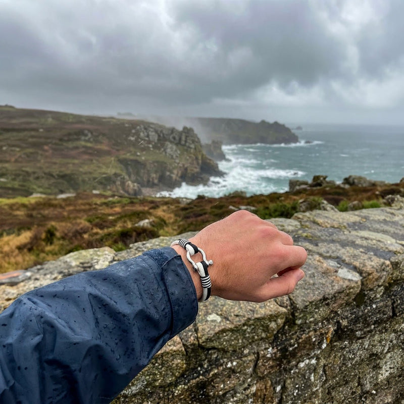 Bracelet nautique noir et blanc en nylon tressé avec fermoir manille en acier inoxydable, style breton élégant.