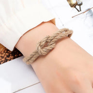 Bracelet beige en corde tressée avec nœud et fermoir aimanté, style naturel, porté au poignet.