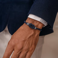 Bracelet nœud marin ajustable en nylon bleu marine porté au poignet masculin avec costume bleu marine.