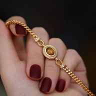 Bracelet femme en acier inoxydable doré avec pierre œil de tigre ovale sertie de motifs raffinés.