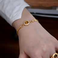 Bracelet Primrose en acier inoxydable doré avec œil de tigre ovale sur poignet féminin.
