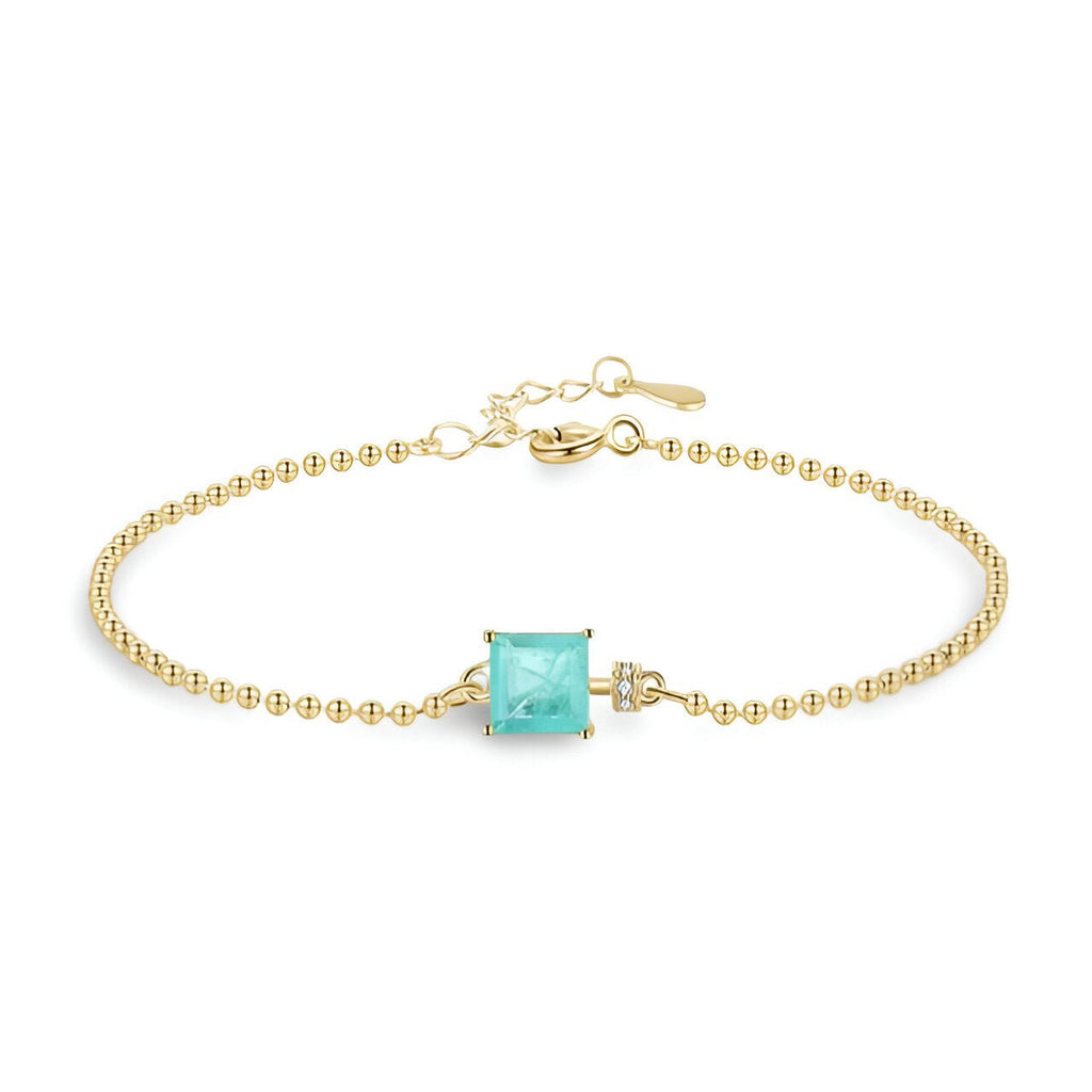 Bracelet fin en or avec pierre carrée bleue sertie et chaîne à billes délicates.