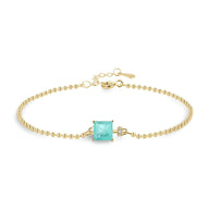 Bracelet fin en or avec pierre carrée bleue sertie et chaîne à billes délicates.