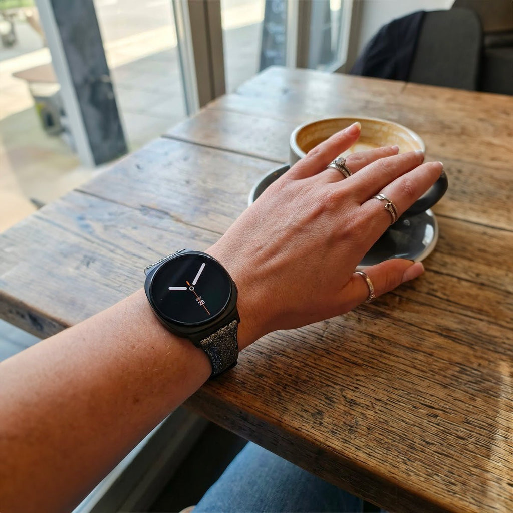 Bracelet pailleté noir en cuir souple avec boucle métal argentée sur Galaxy Watch 8, poignet féminin.