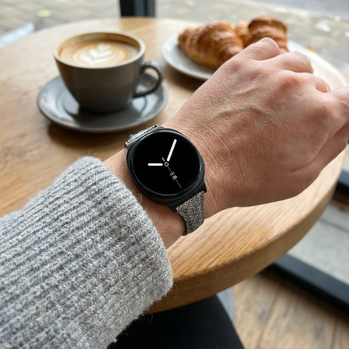 Bracelet pailleté noir en cuir souple avec boucle métal, porté sur Galaxy Watch 8 au poignet féminin.