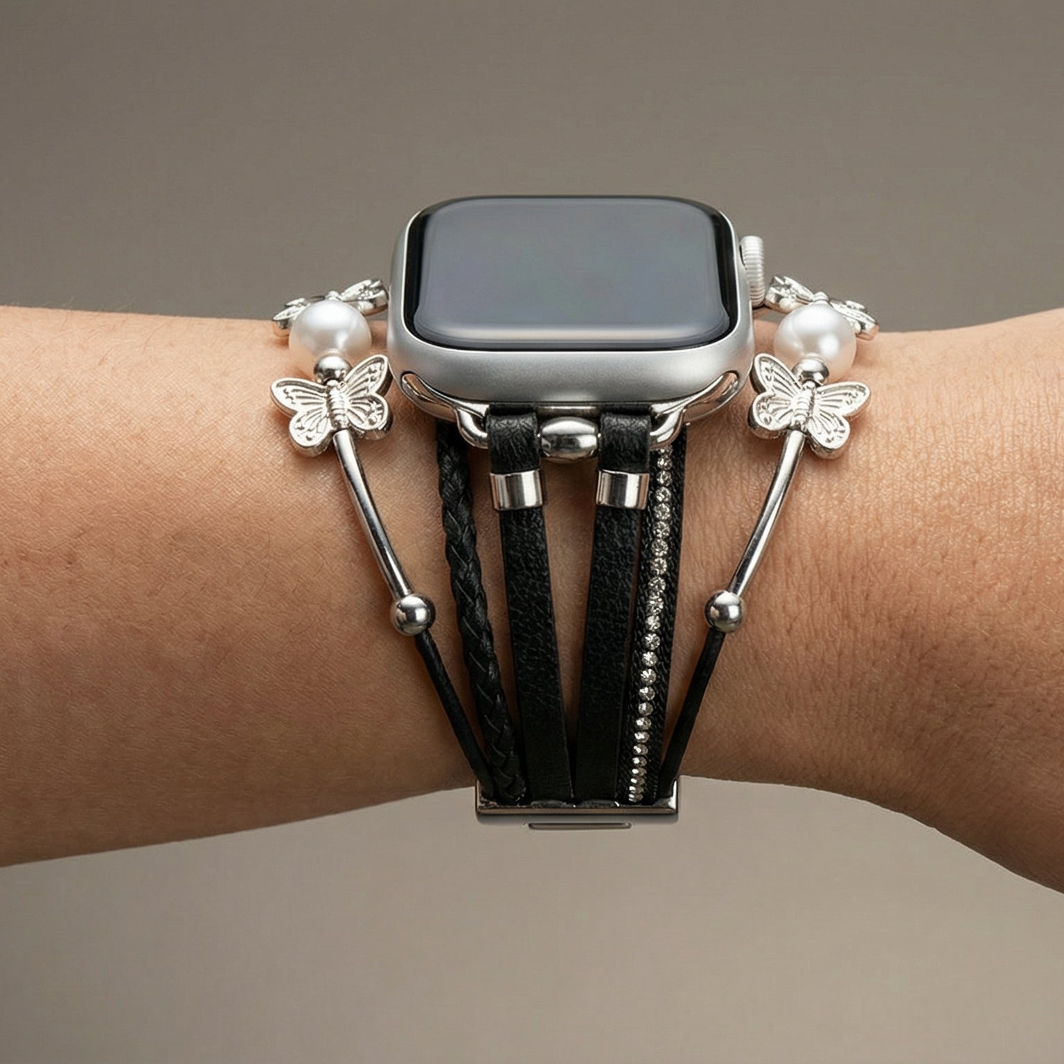 Bracelet pour Apple Watch multi-brins en cuir noir avec perles blanches et breloques papillon argentées, fermoir métallique.