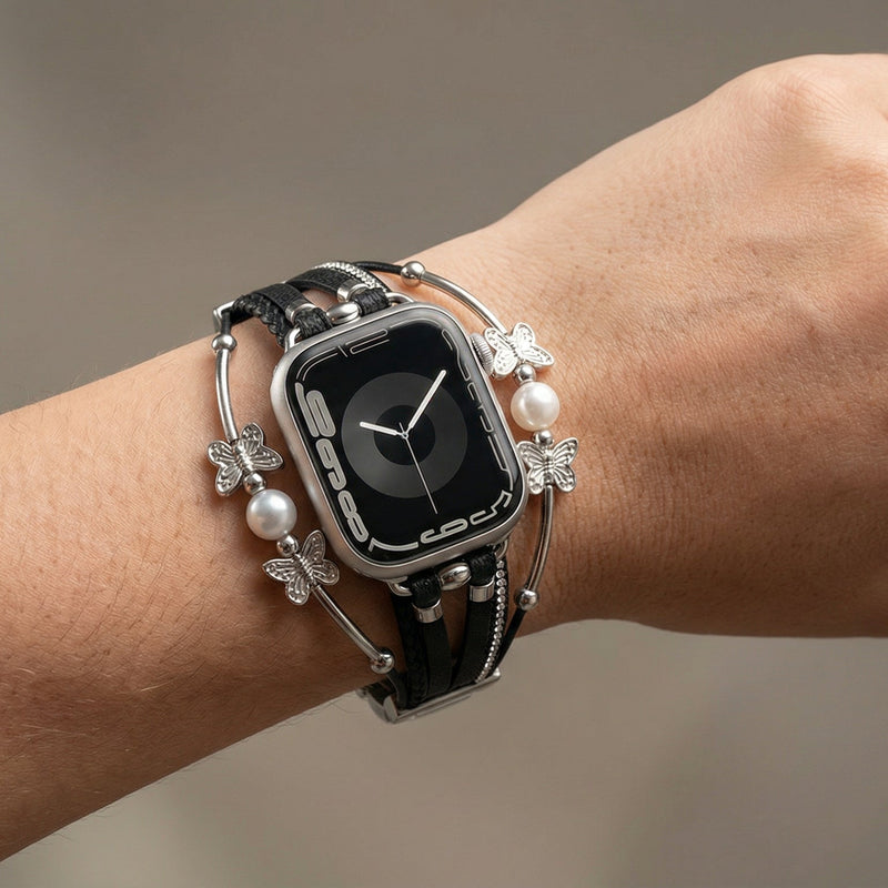 Bracelet papillon noir en cuir multi-brins avec perles blanches et fermoir métallique élégant sur Apple Watch.