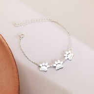 Bracelet chaîne argentée avec trois pendentifs en forme de patte gravés personnalisés, style fin et délicat.