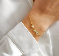 Bracelet fin en acier inoxydable doré avec trois pendentifs en forme de pattes délicates, porté au poignet féminin.