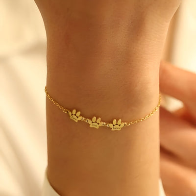 Bracelet fin en acier inoxydable doré avec trois pendentifs pattes délicats sur chaîne ajustable.