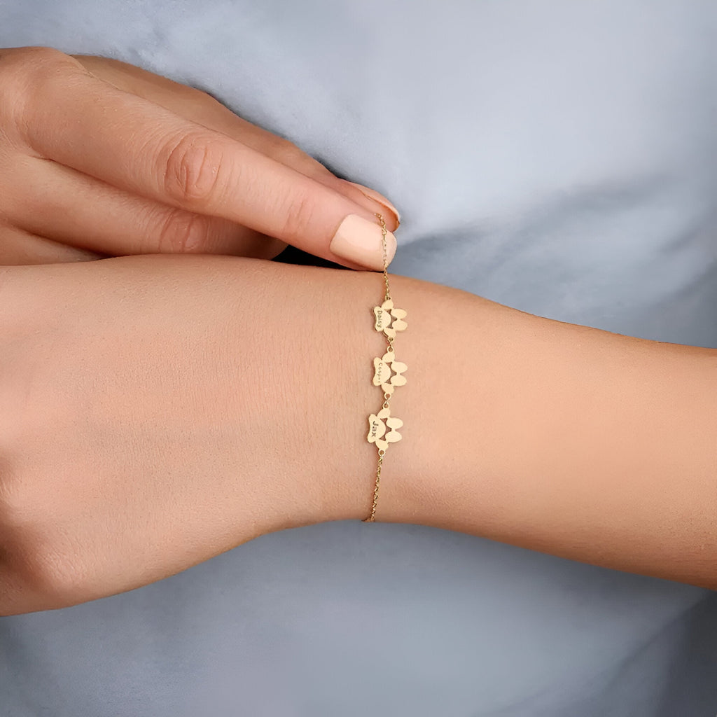 Bracelet fin en acier inoxydable doré avec trois charms en forme de patte, longueur ajustable.