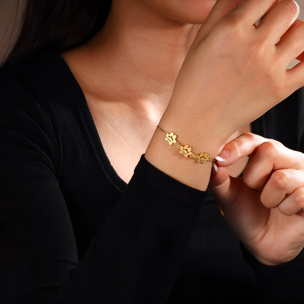 Bracelet en acier inoxydable doré avec pendentifs pattes sur poignet féminin, style délicat.