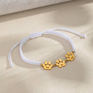 Bracelet blanc en nylon tressé avec trois pendentifs pattes dorés en acier inoxydable.