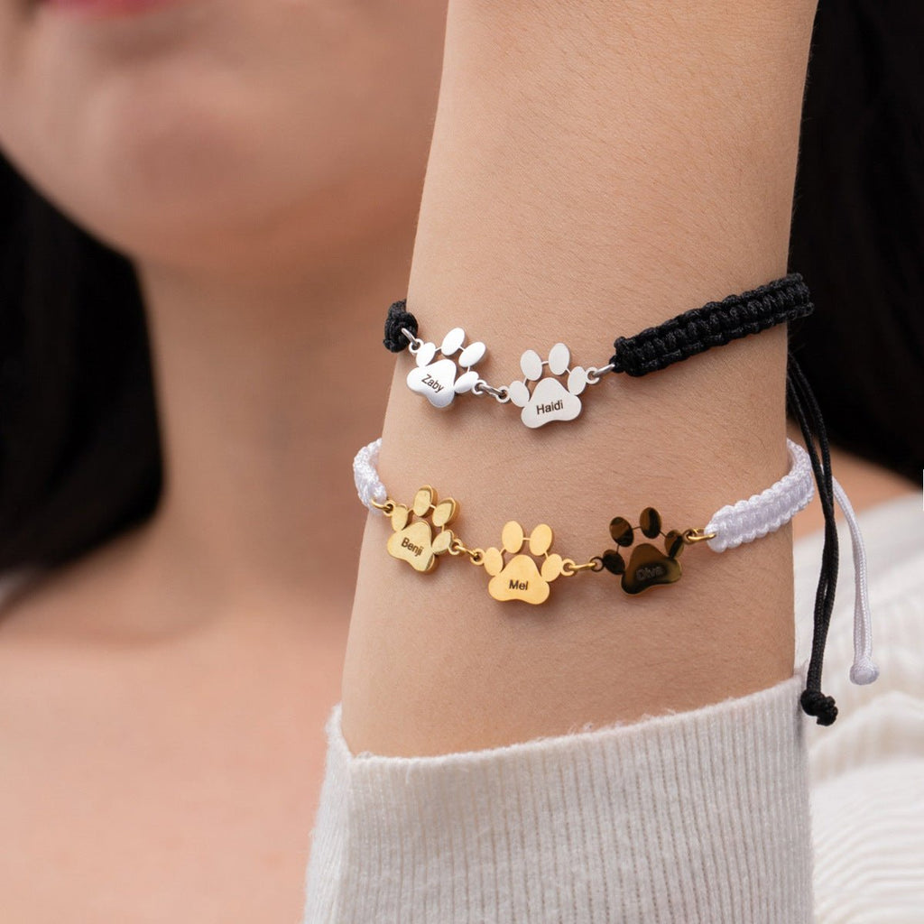 Deux bracelets en nylon à patte de chien, l’un noir et argent, l’autre blanc avec détails dorés et noirs, style mixte.